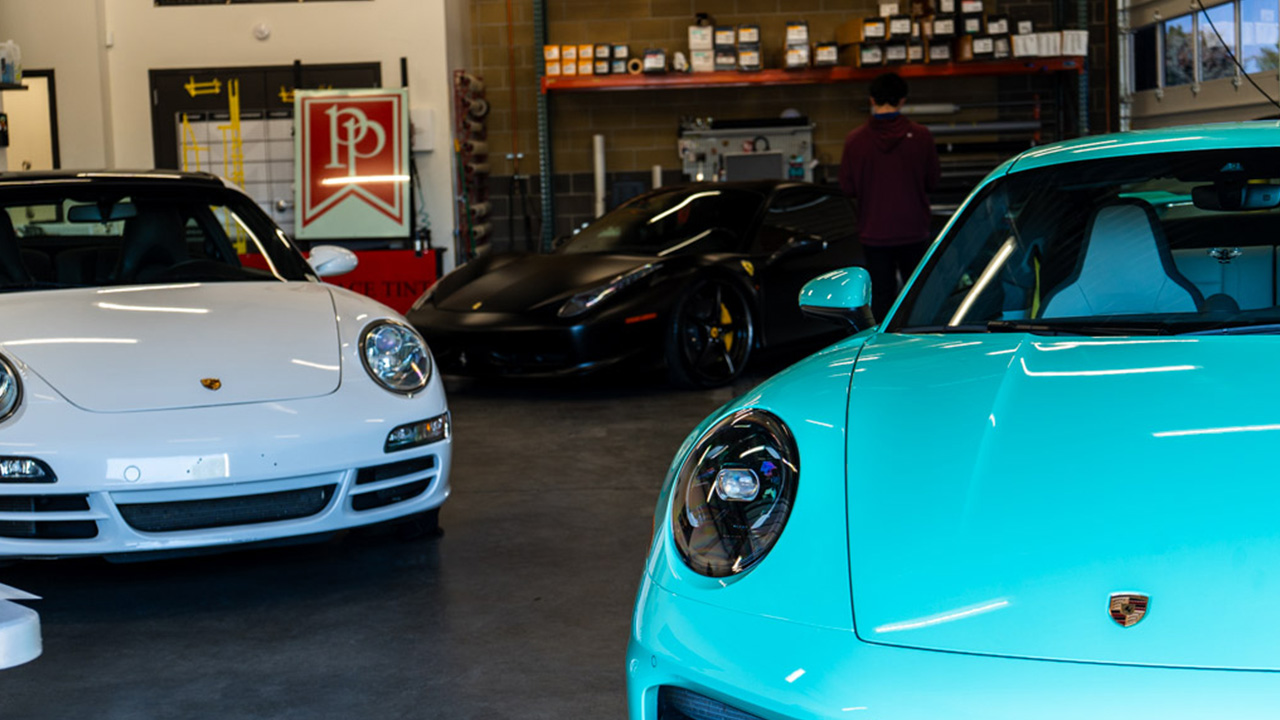 A turquoise Porsche, white Porsche, and black Ferrari displayed inside Park Place