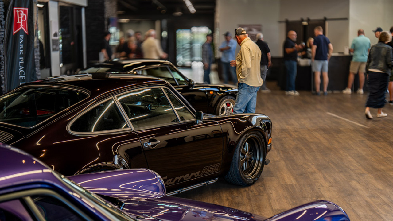 Classic Porsches displayed inside the Park Place showroom as guests gather nearby