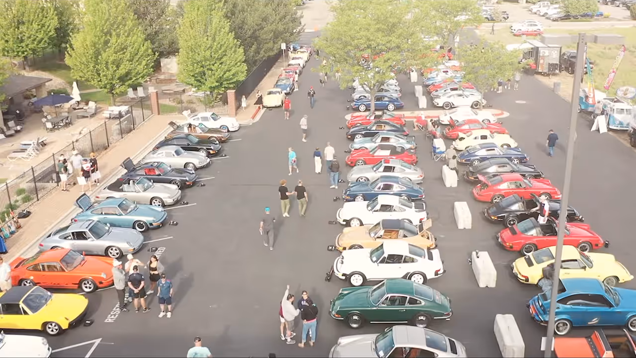Rows of colorful Porsches along a tree-lined gathering space