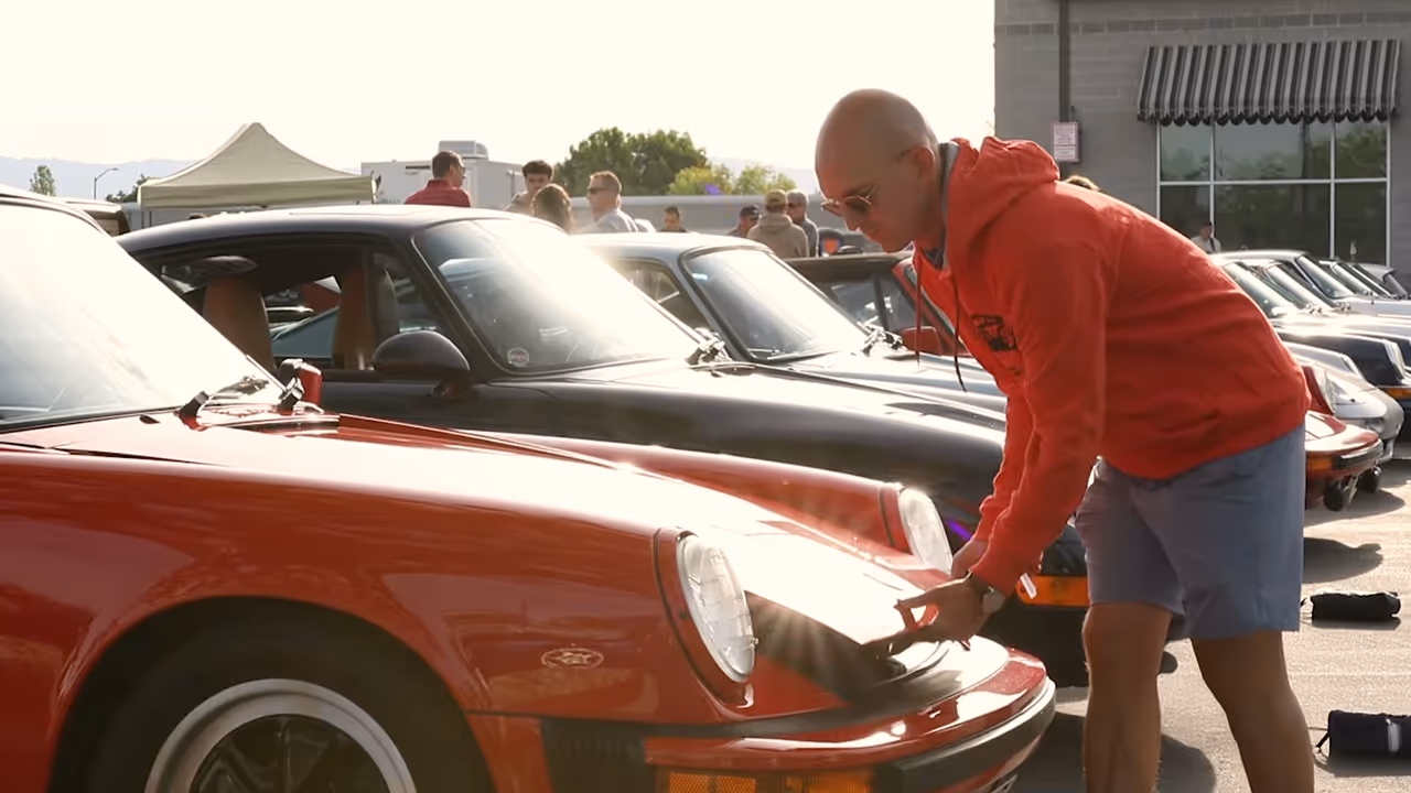 A visitor looking closely at a red classic Porsche