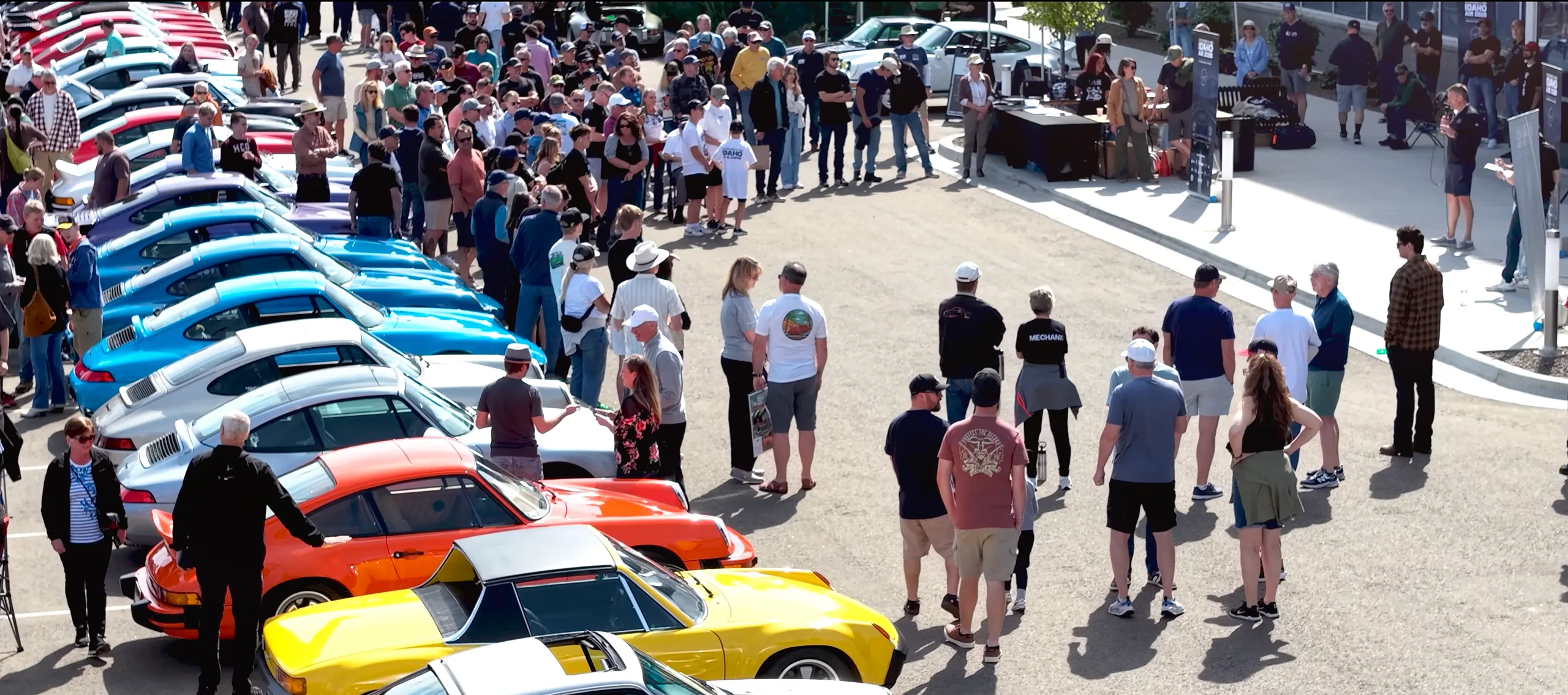 Hundreds of attendees gathered around a long row of colorful air-cooled Porsches during the Idaho Air 2026 opening remarks
