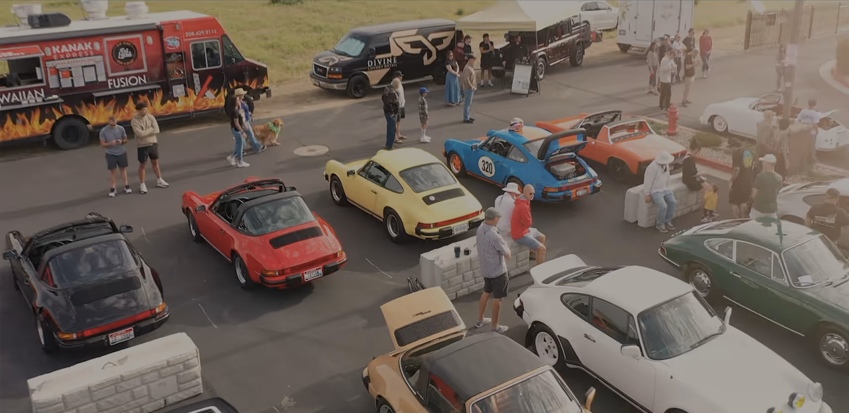 Colorful air-cooled Porsches, visitors and food trucks viewed from above