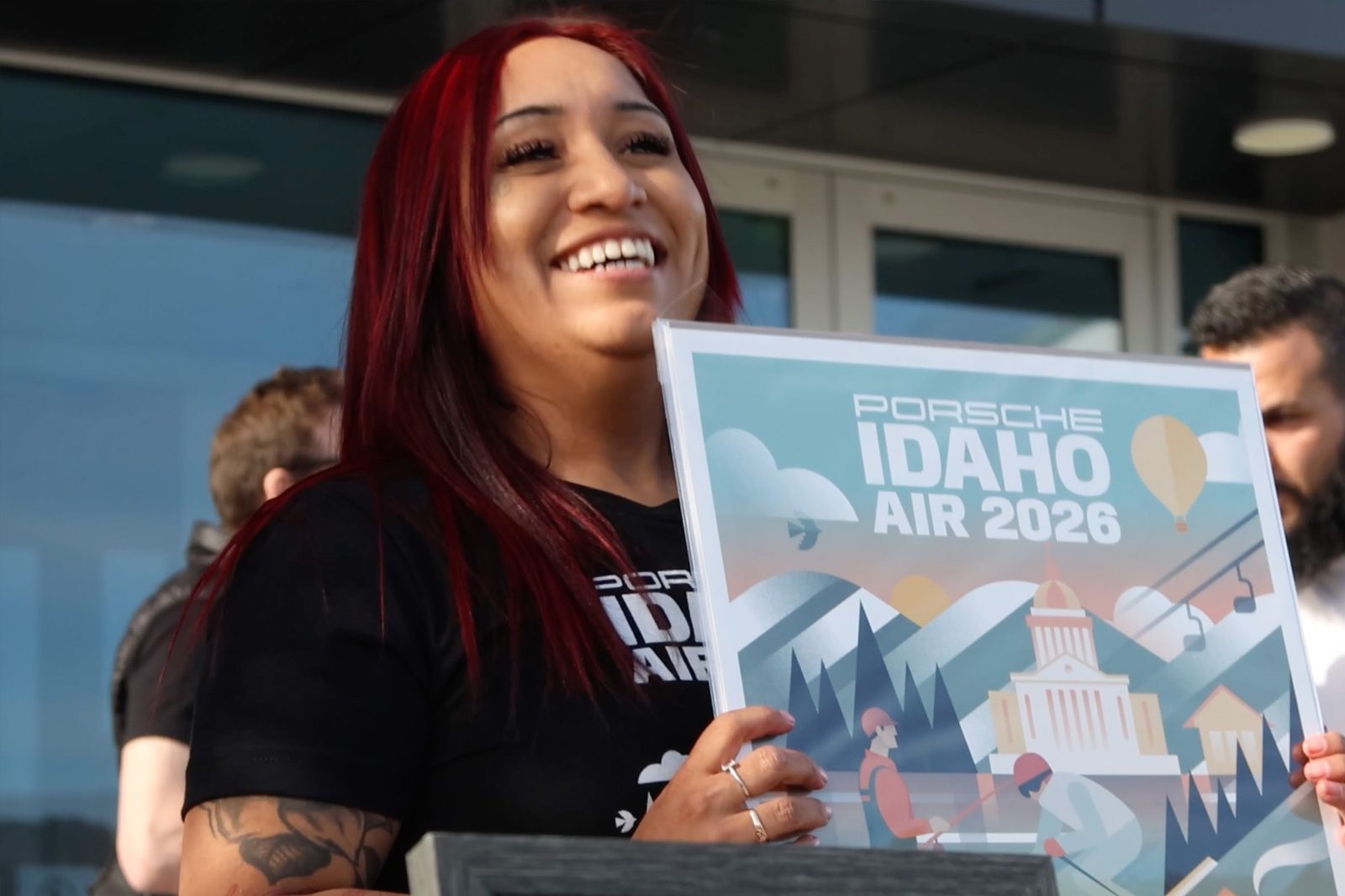 An Idaho Air volunteer smiles as she holds up an Idaho Air poster