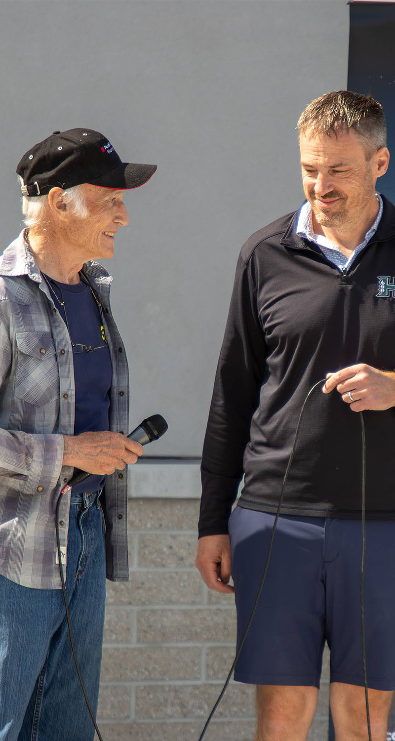 Two owners talking and laughing, one holding a microphone