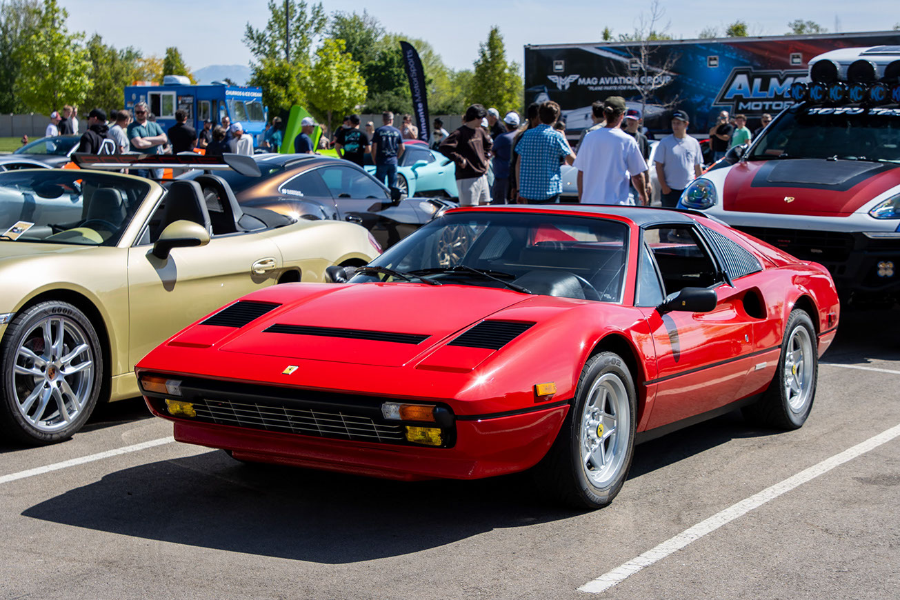 Red classic Ferrari on the modern and exotics field at Idaho Air 2026, with the crowd and food trucks behind